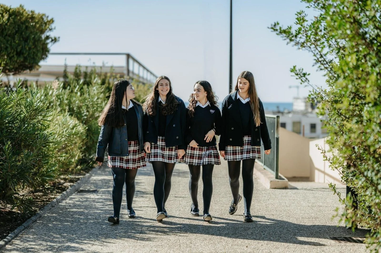 Cuatro alumnas con uniforme pasean por un camino del campus